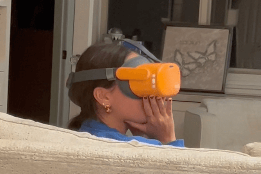 A teenager sitting on the sofa wearing an orange pair of Reloom VR googles.